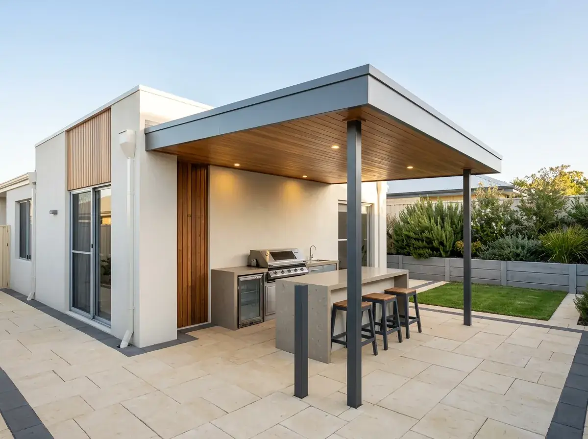 A flat roof patio over a built-in outdoor kitchen, the flat roofline and timber lined ceiling above a stone benchtop and bar stools
